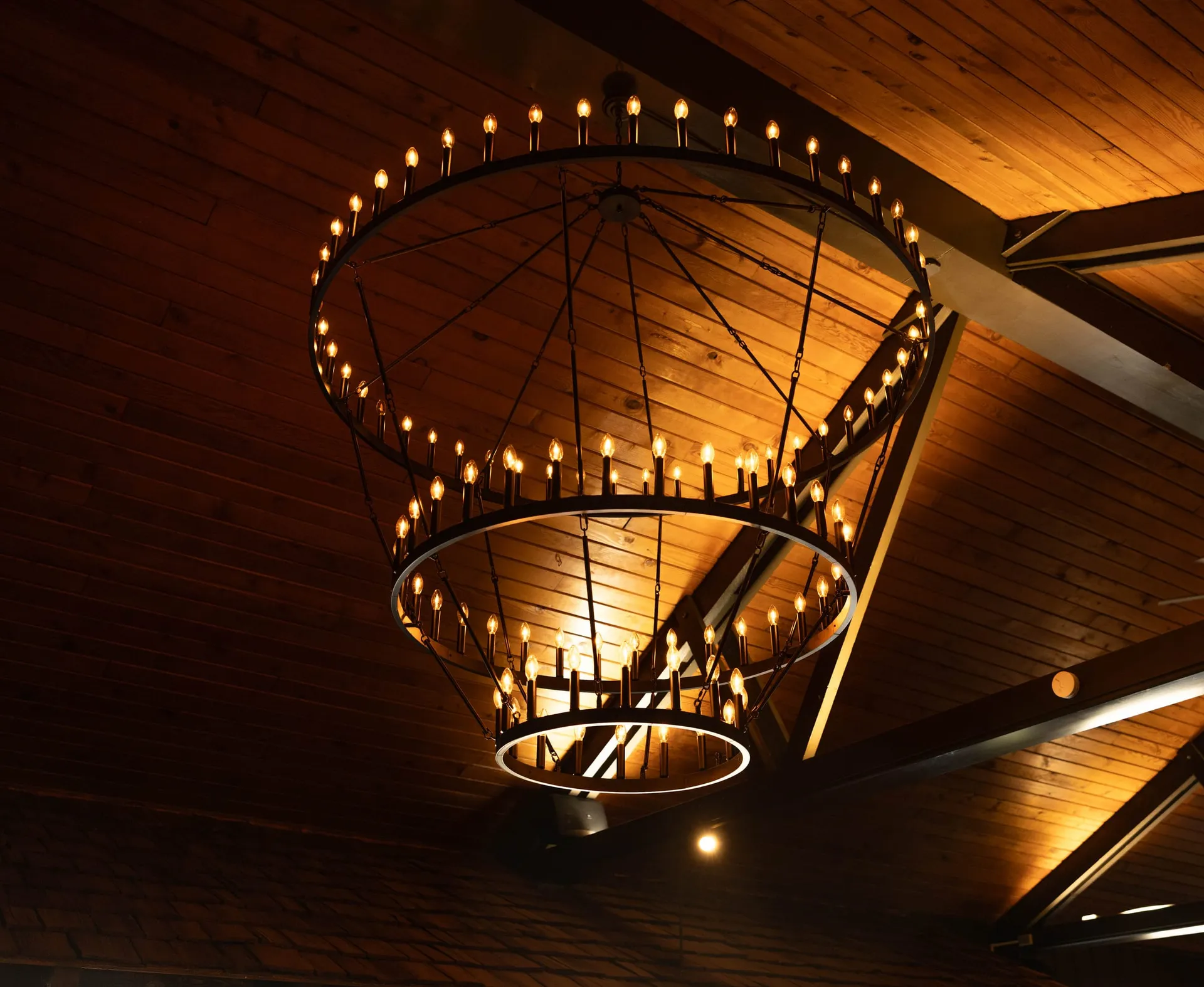Ring chandelier glowing beneath the wood-beamed ceiling of The Great Room