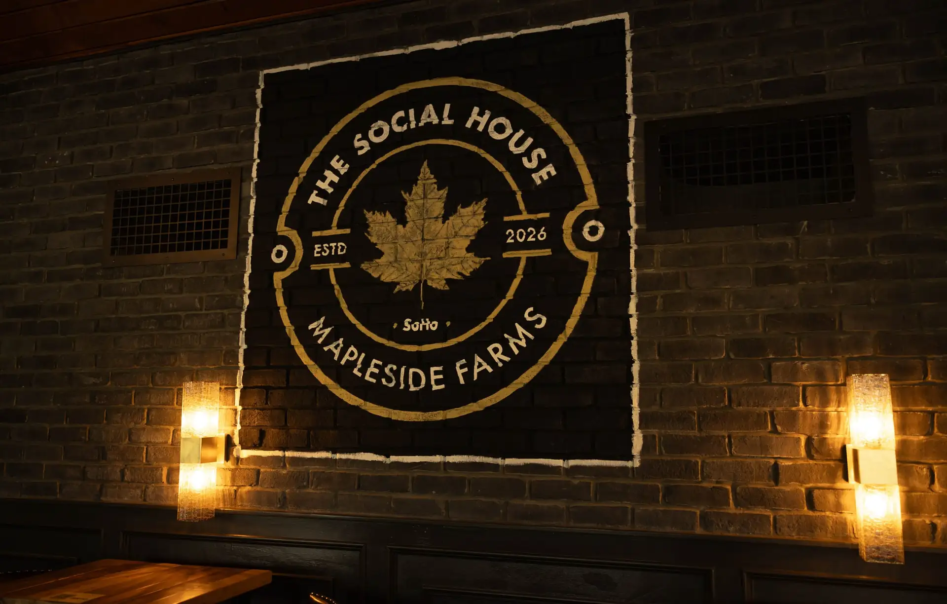 The Social House maple leaf emblem on the brick wall of The Great Room