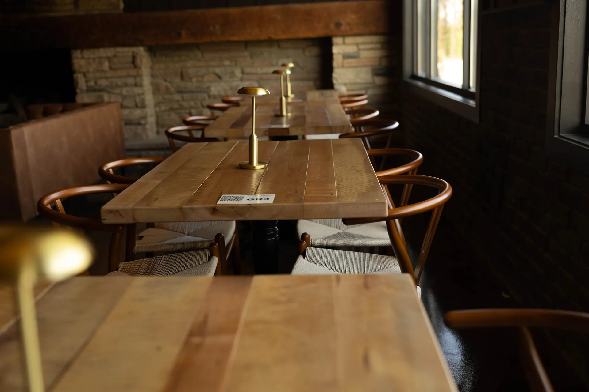 Long communal tables with brass lamps in The Great Room