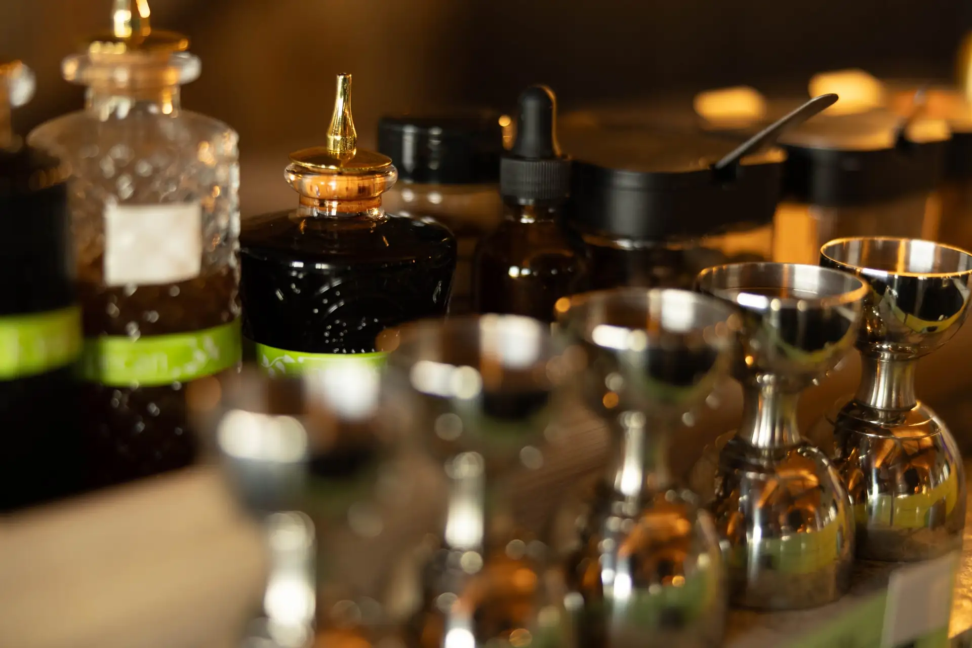 Bitters and silver jiggers lined up on the bar