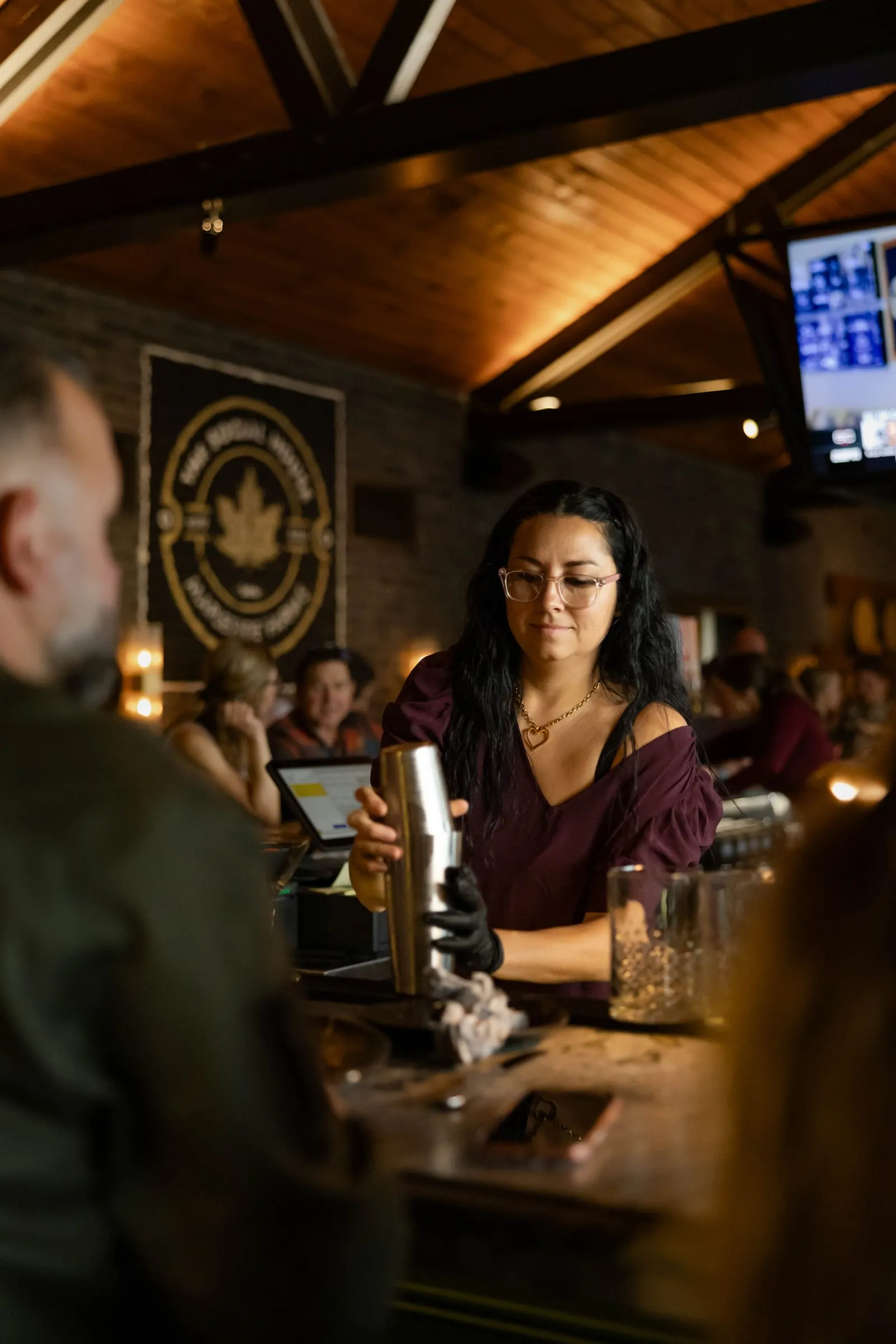A guest smiling at the bar beneath The Social House emblem