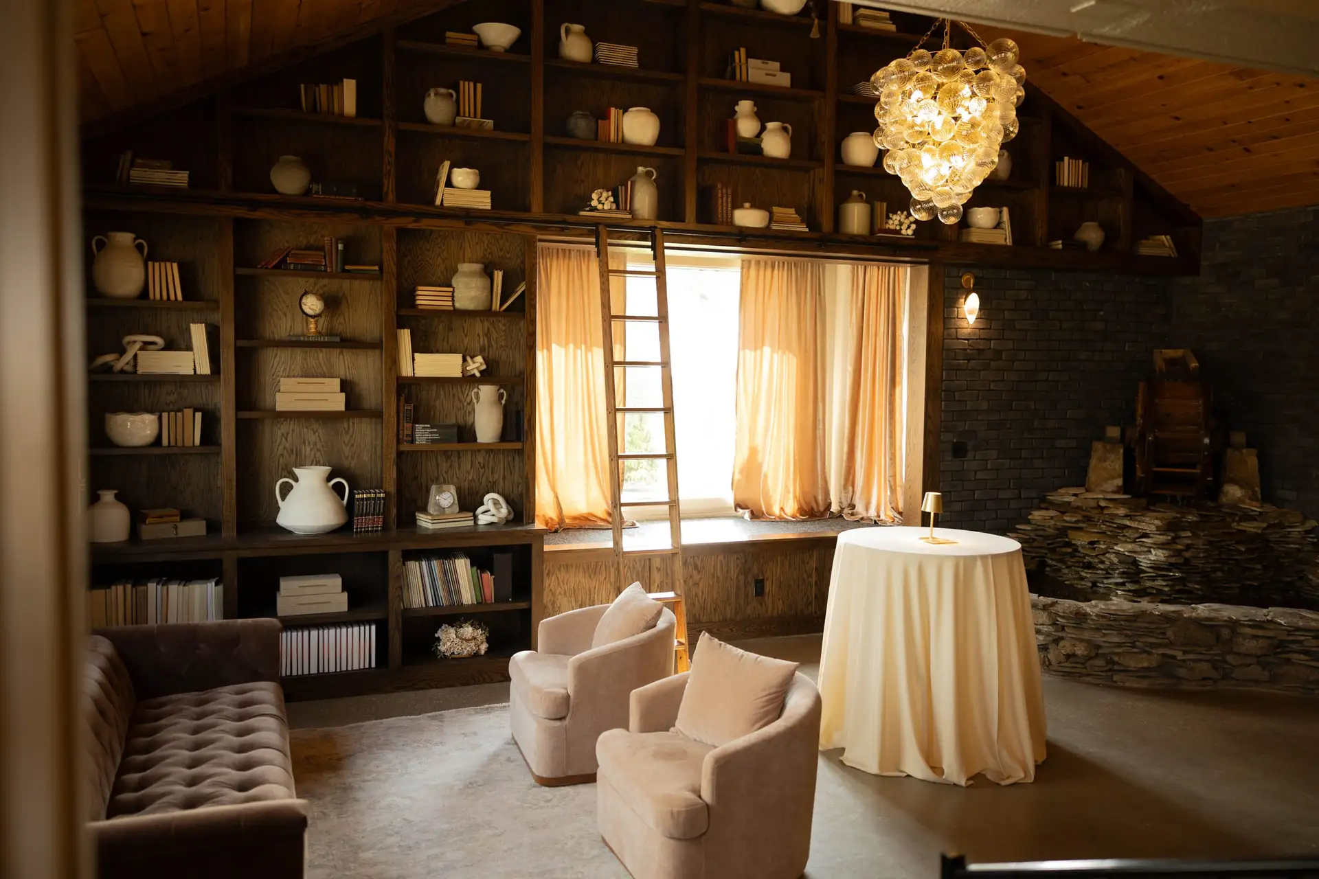 Bookshelves, a rolling ladder and armchairs in The Library at The Social House, Mapleside Farms
