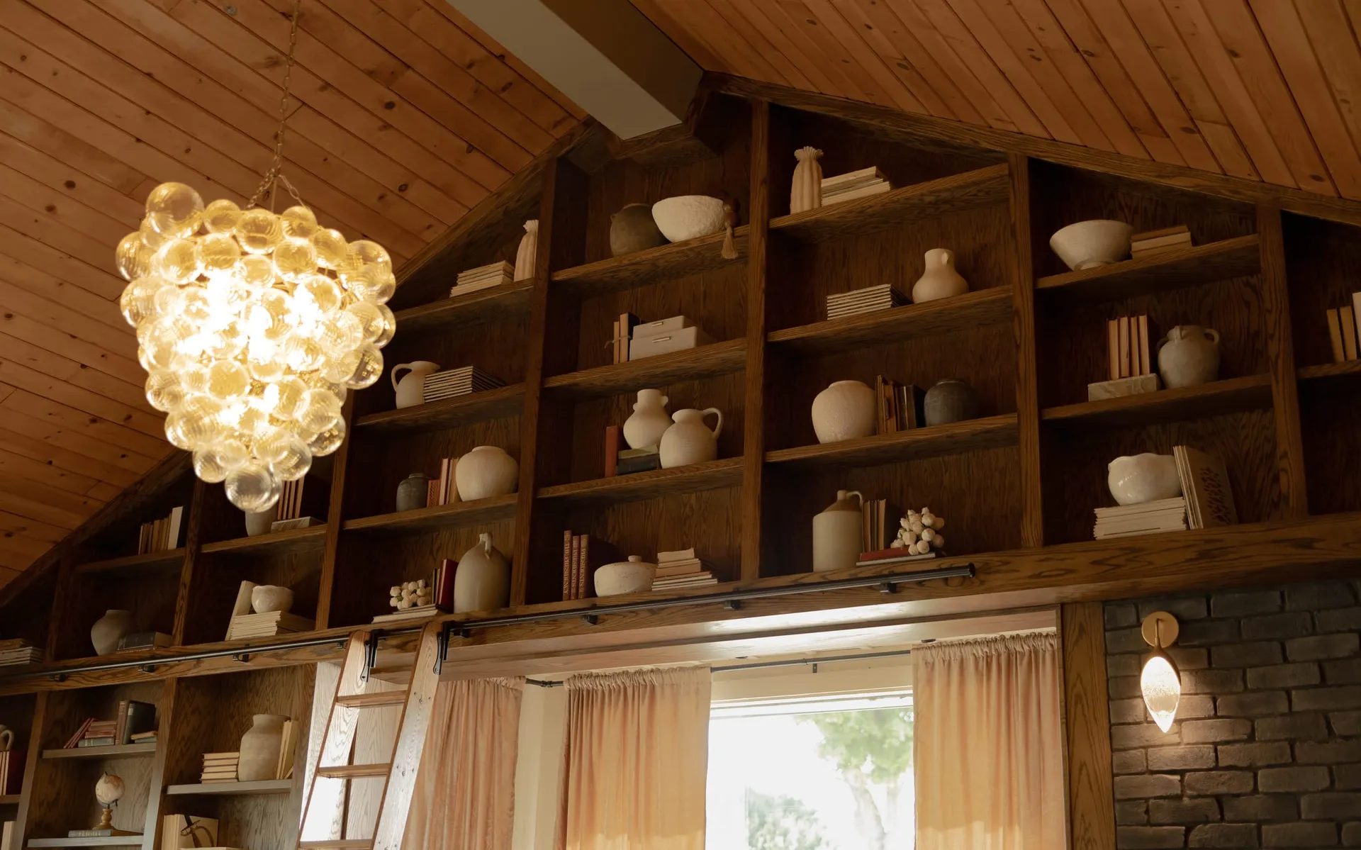 Shelves of pottery and books beneath the glass chandelier in The Library