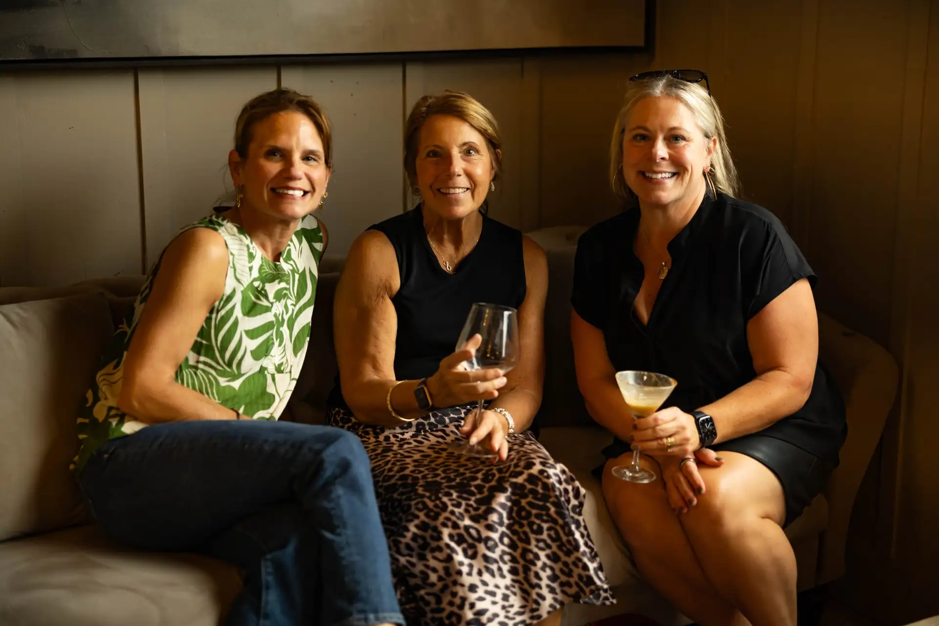 Three friends with drinks on a sofa in The Library