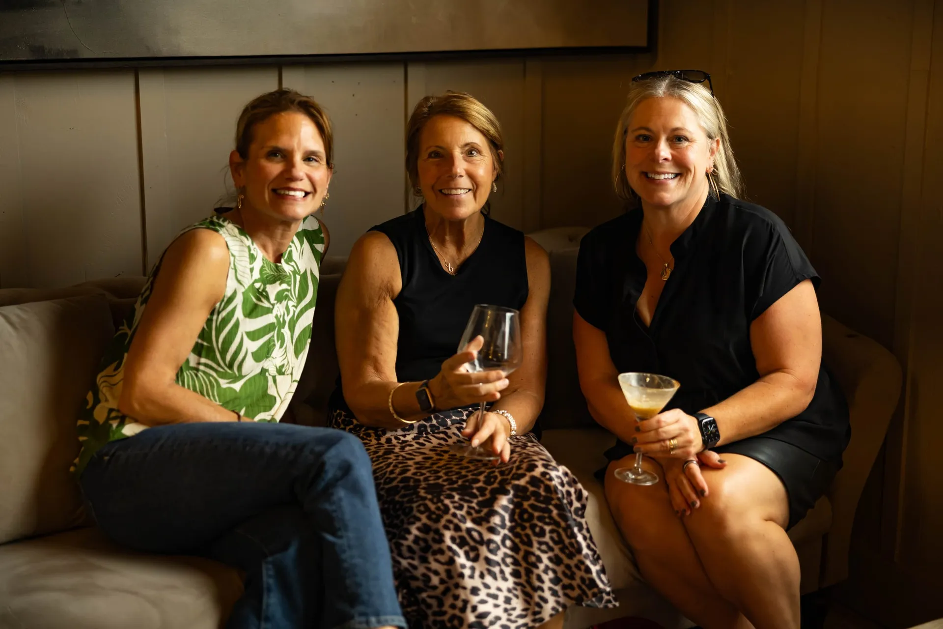Three friends with drinks on a sofa in The Library
