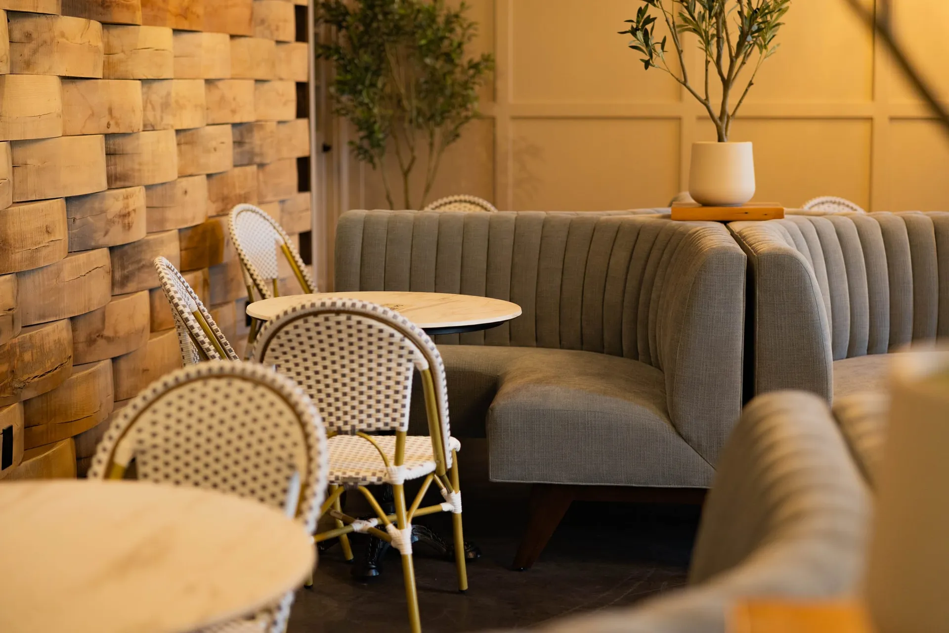 Woven bistro chairs and banquettes beside the barrel-stave wall in The Press